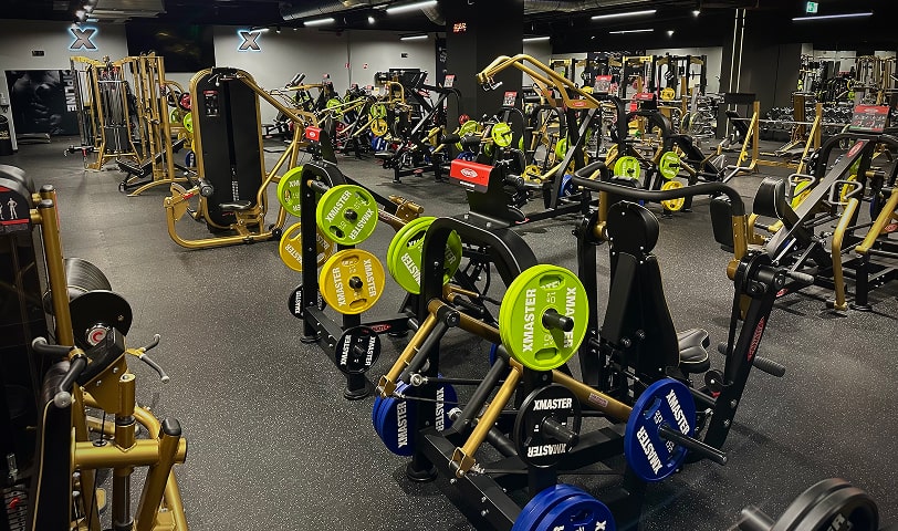 Strefa maszyn z nowoczesnym sprzętem siłowym umożliwiającym kompleksowy trening całego ciała.