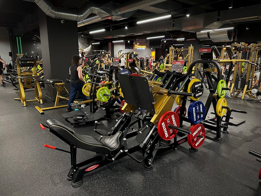 Suwnica oraz inne nowoczesne maszyny treningowe na strefie maszyn w klubie fitness.